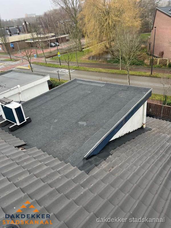 Plat dak met bitumen dakbedekking naast schuin pannendak in Stadskanaal
