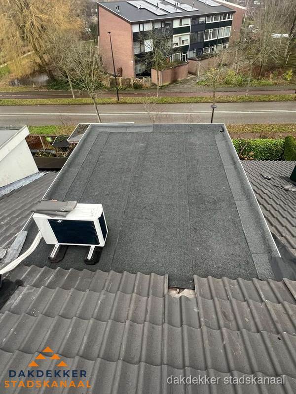 Plat dak inspectie met bitumen bedekking naast schuin pannendak in Stadskanaal
