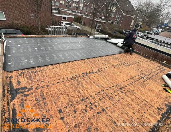 Dakdekker legt onderlaag op plat dak met houten constructie in Stadskanaal