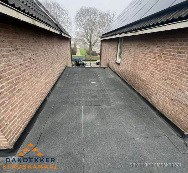 Plat dak met bitumen dakbedekking tussen bakstenen muren in Stadskanaal Plat dak met bitumen dakbedekking tussen bakstenen muren in Stadskanaal